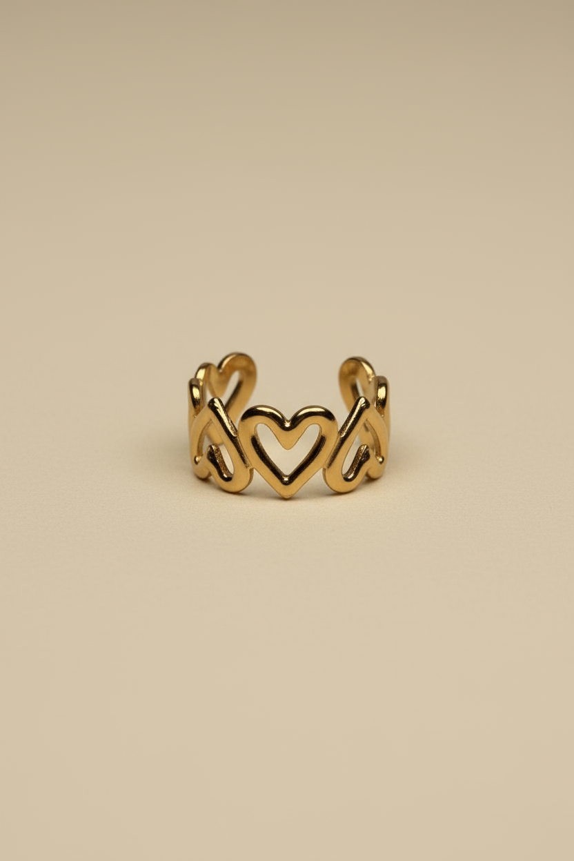 Gold ring with heart designs on a beige background