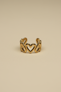 Gold ring with heart designs on a beige background