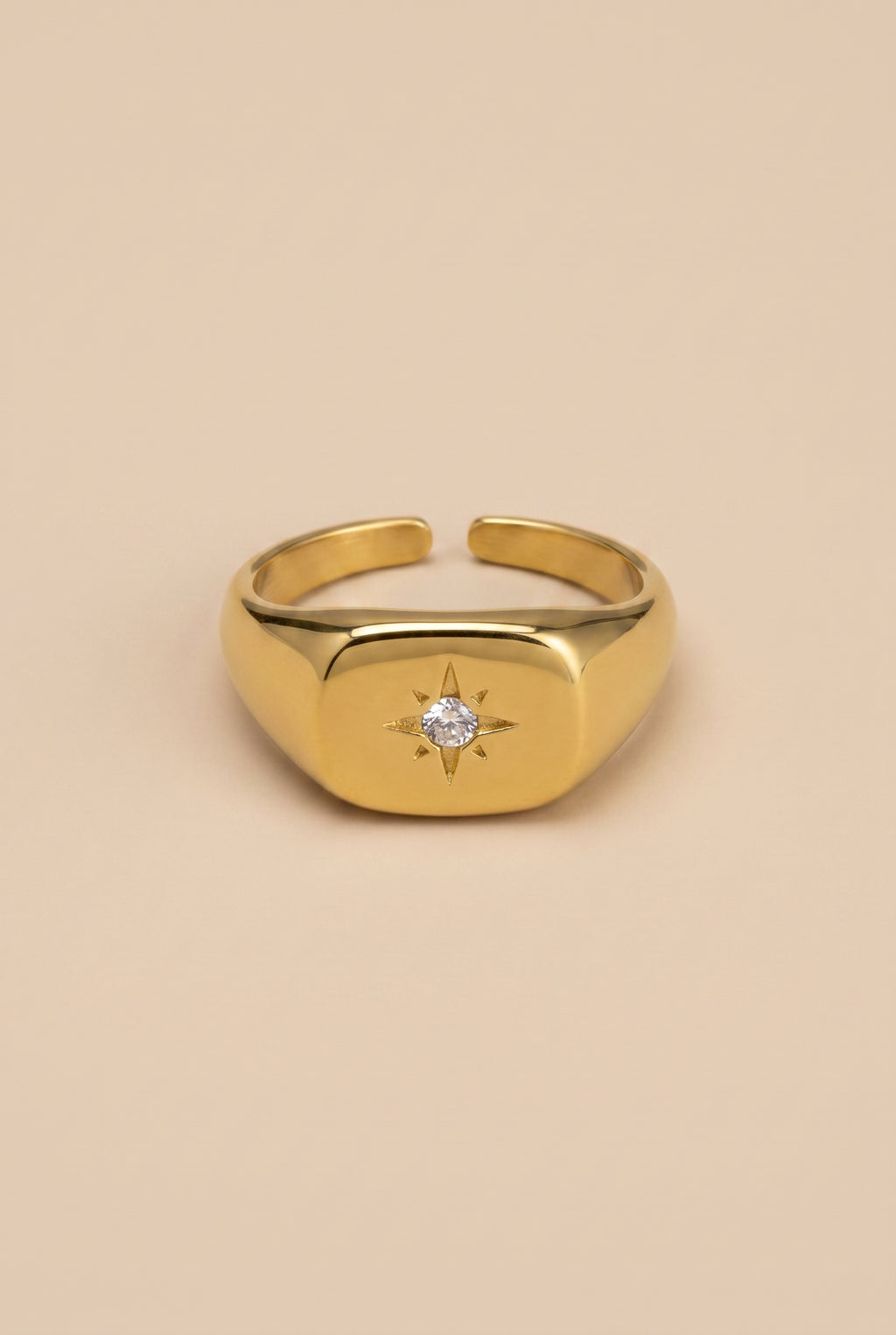 Gold ring with a diamond on a beige background