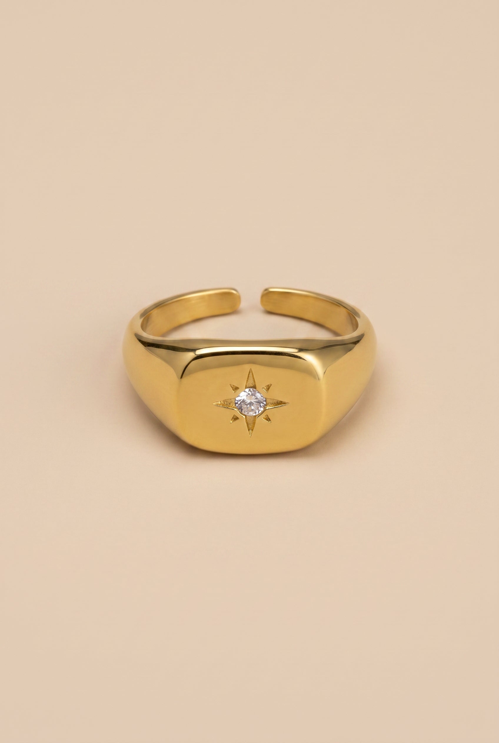 Gold ring with a diamond on a beige background