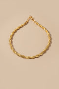 Gold braided necklace on a beige background