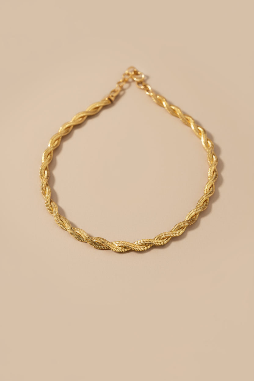 Gold braided necklace on a beige background