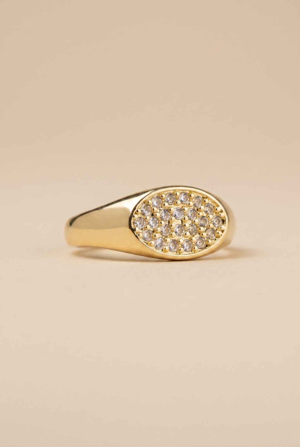 Gold ring with diamond accents on a beige background