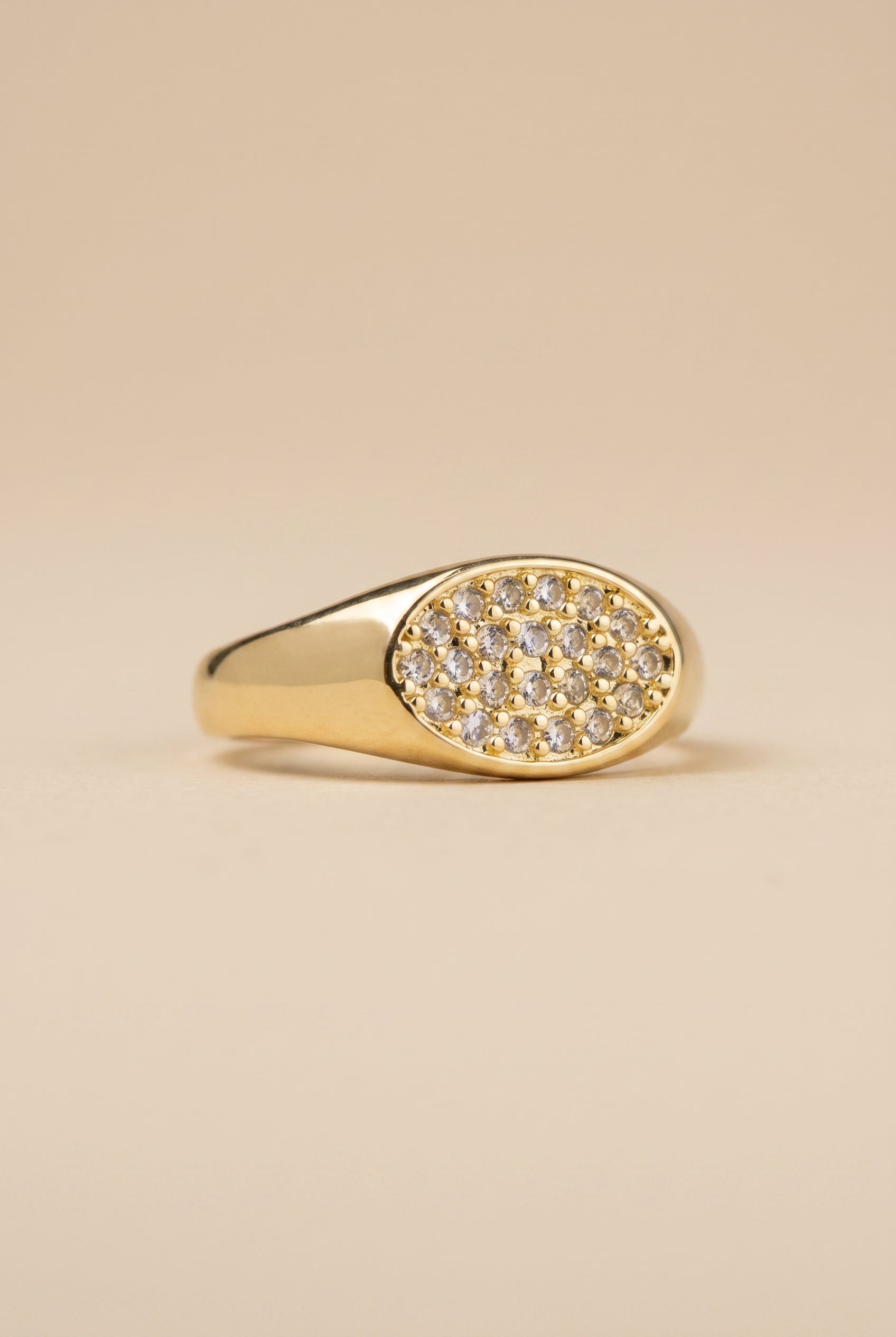 Gold ring with diamond accents on a beige background