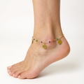 Ankle with a gold anklet featuring colorful beads on a white background