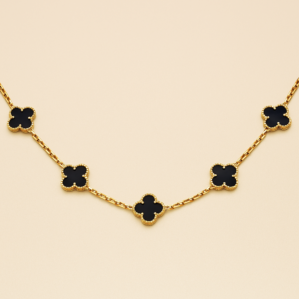 Gold necklace with black clover-shaped pendants on a beige background