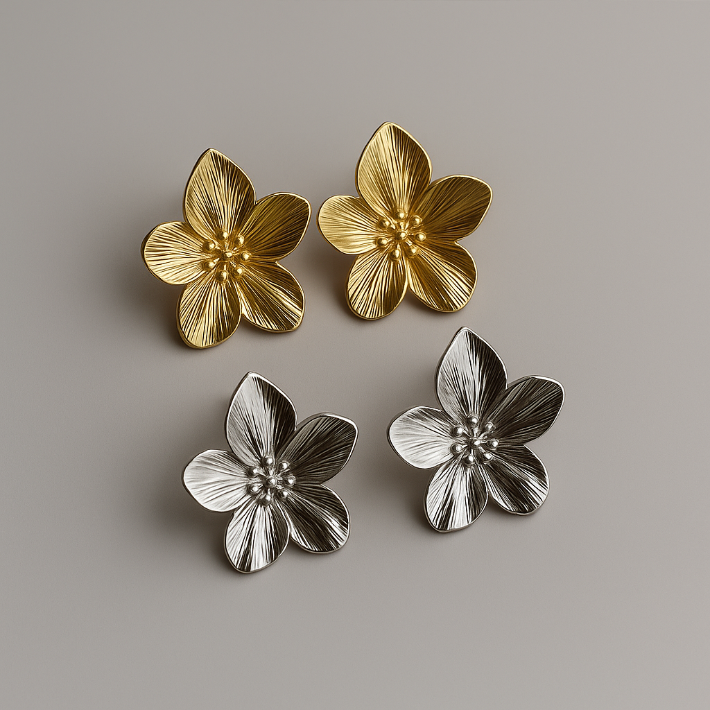 Two pairs of gold and silver flower-shaped earrings on a gray background
