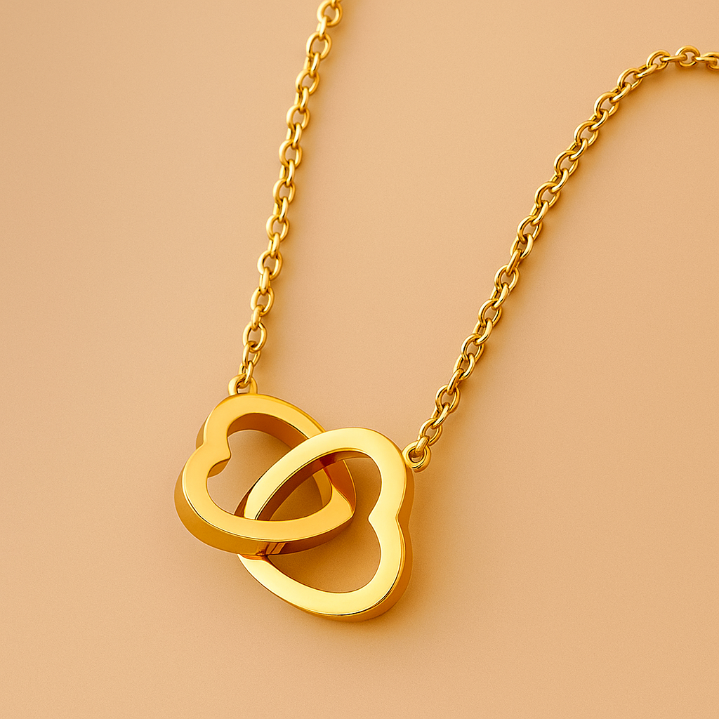 Gold necklace with interlocking heart pendants on a beige background