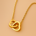 Gold necklace with interlocking heart pendants on a beige background