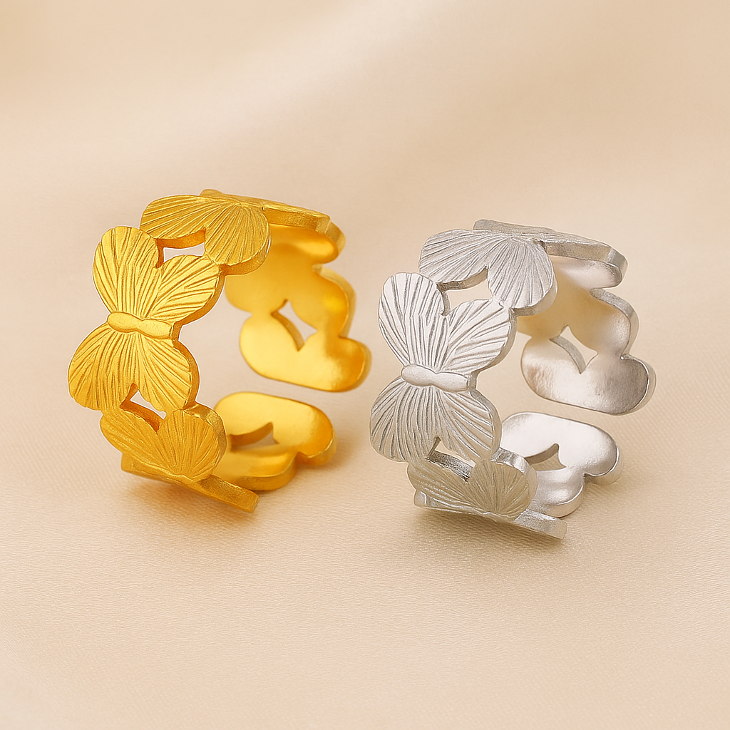 Gold and silver rings with butterfly designs on a beige background