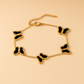 Gold bracelet with black butterfly charms on a beige background