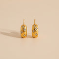 Gold earrings with diamond accents on a beige background
