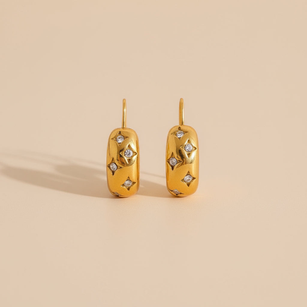 Gold earrings with diamond accents on a beige background