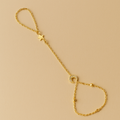 Gold Celestial Handchain with star and circle charms on a beige background