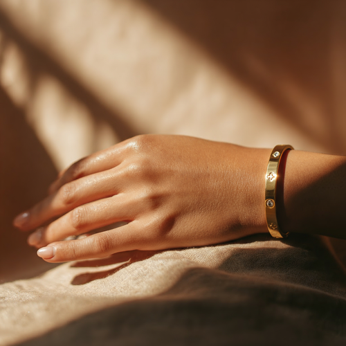 Hand wearing a gold bracelet on a blurred background