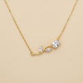 Gold necklace with a leaf-shaped pendant on a beige background