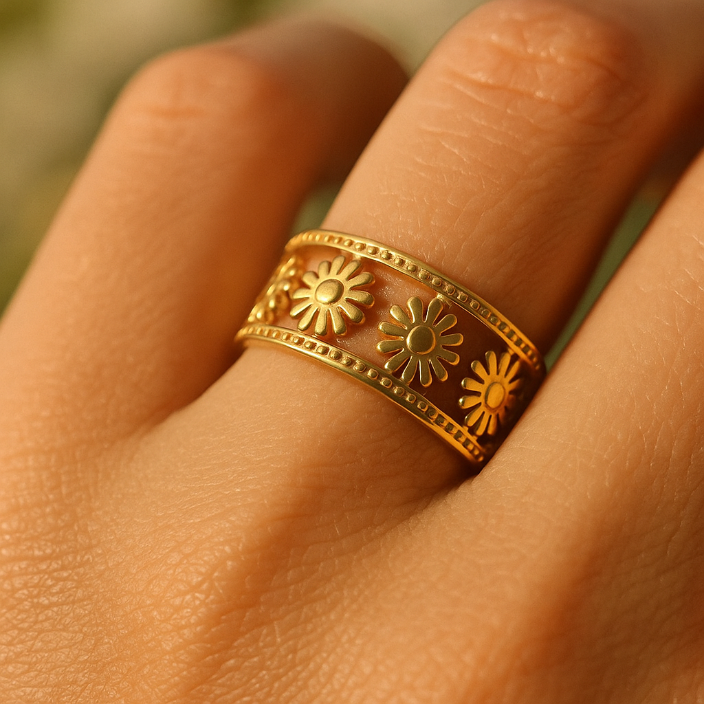 Gold ring with floral designs on a person's finger