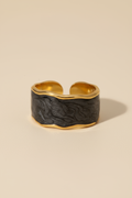 Gold and black ring on a beige background