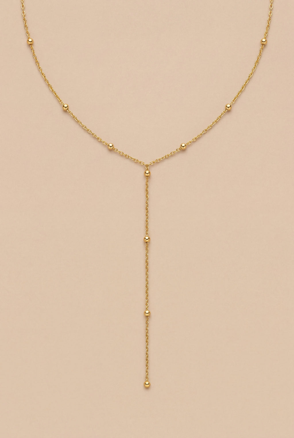 Gold necklace with beads on a beige background