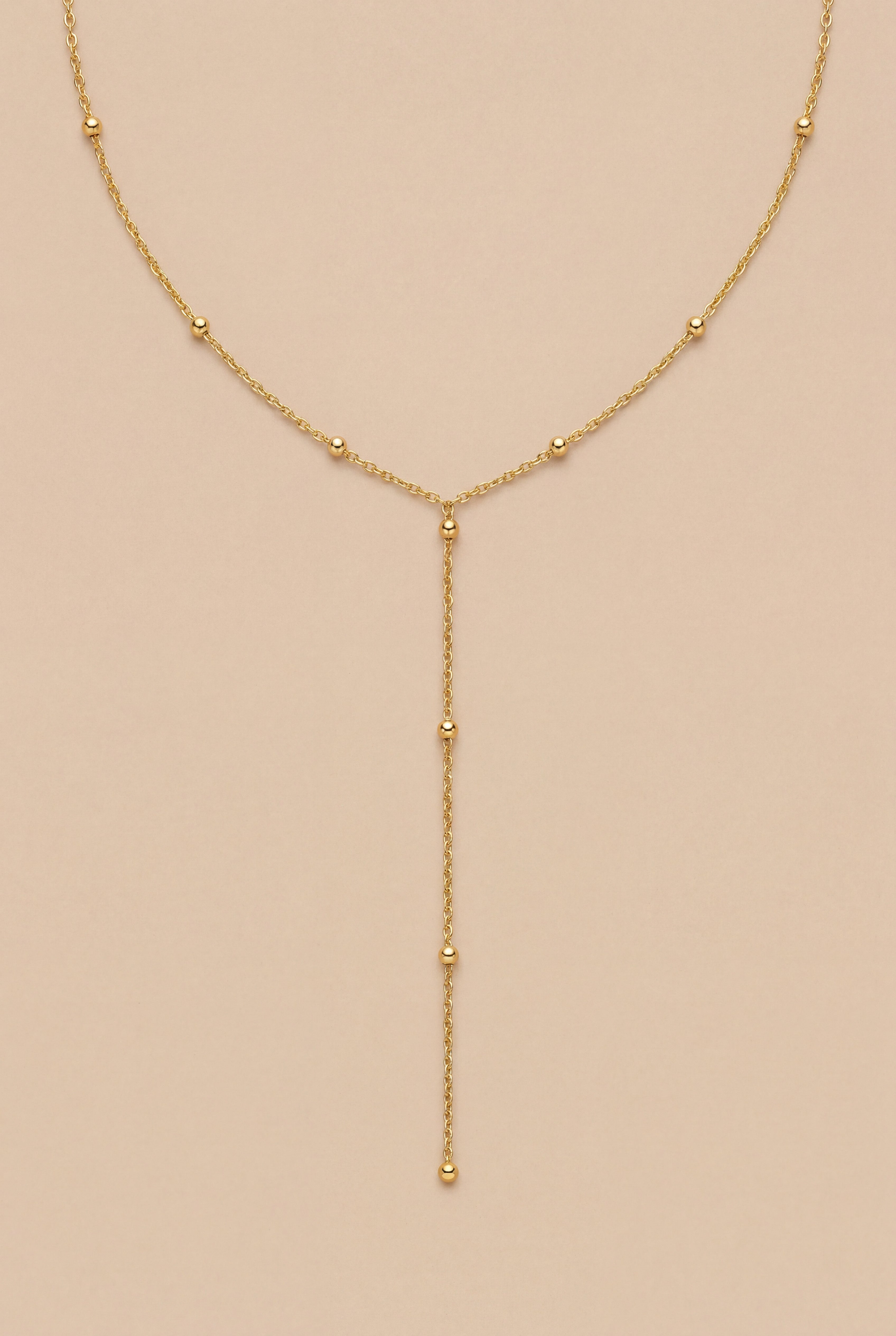 Gold necklace with beads on a beige background