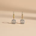 Pair of diamond earrings on a beige background