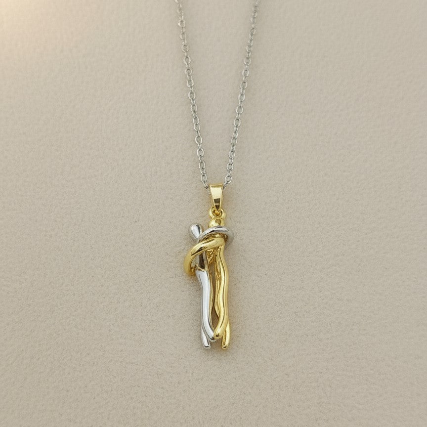 Two-tone gold and silver pendant on a beige background