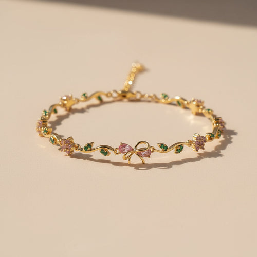 Gold bracelet with floral and bow designs on a beige background