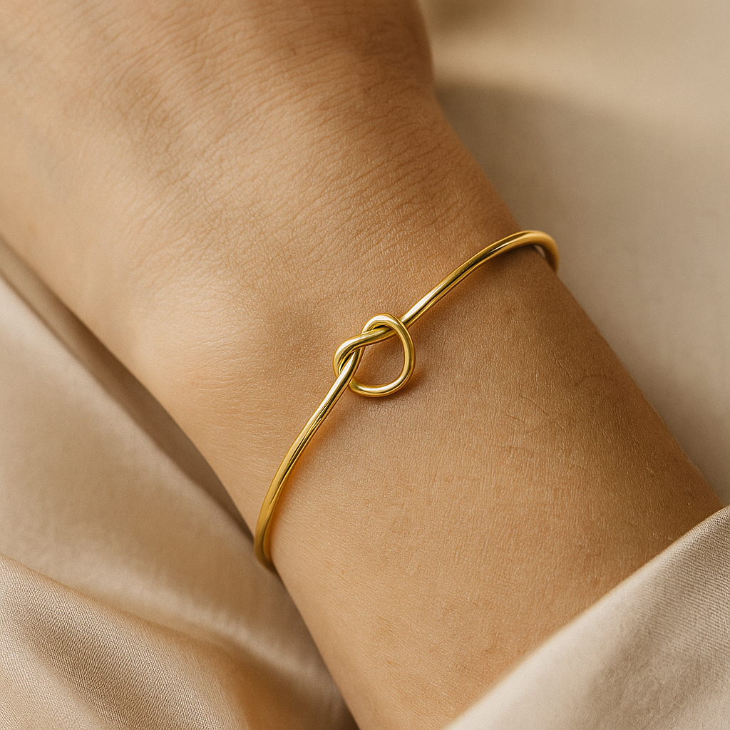 Gold bracelet on a person's wrist with a neutral background