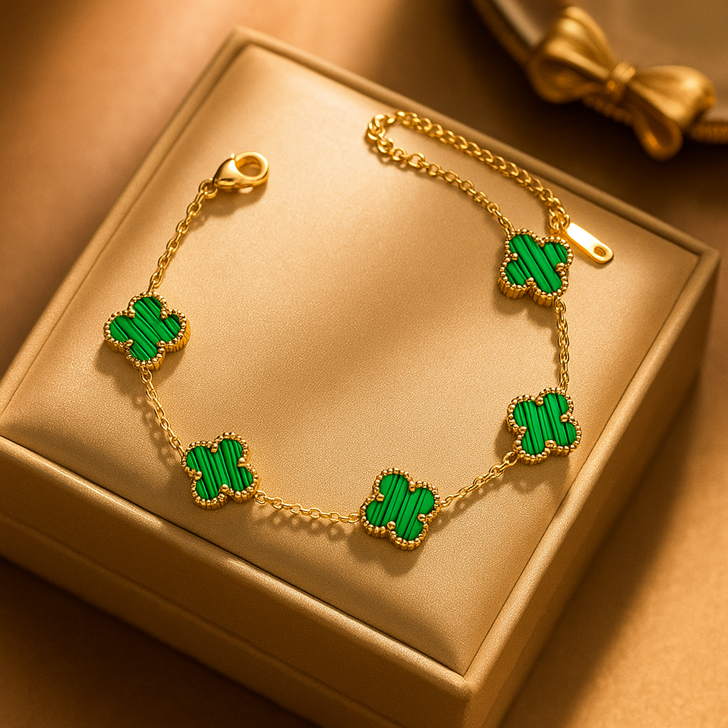 Gold bracelet with green clover-shaped charms on a gold box