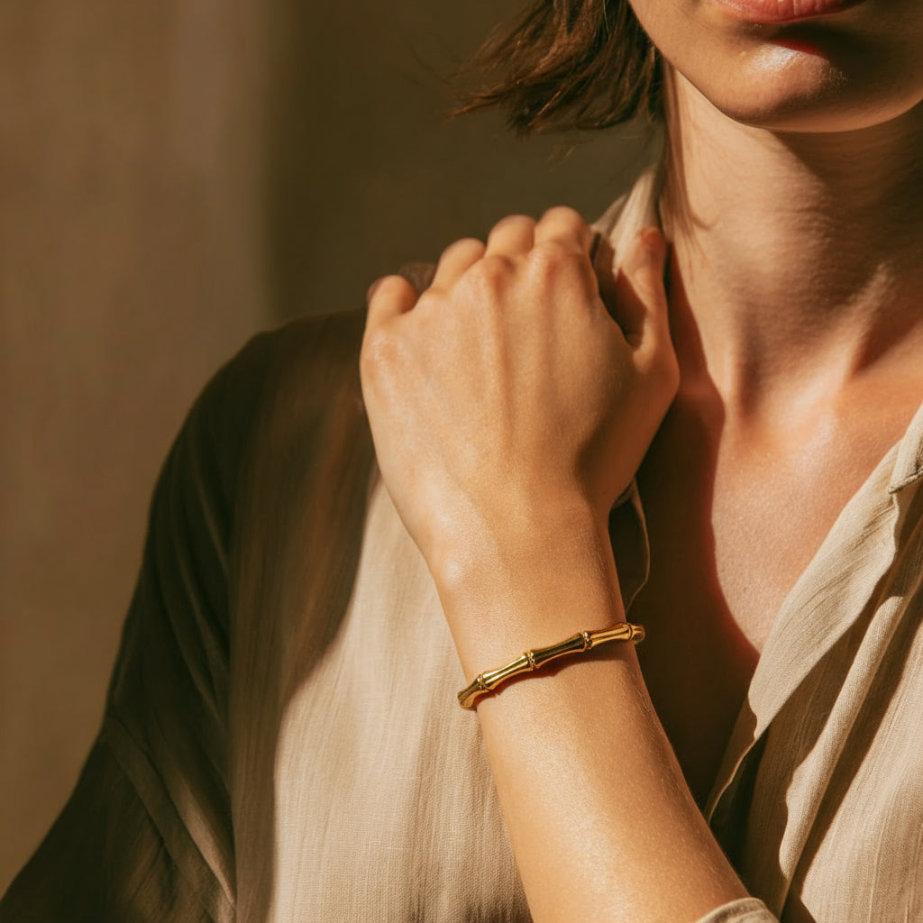 Person wearing a gold bracelet with a soft, warm background