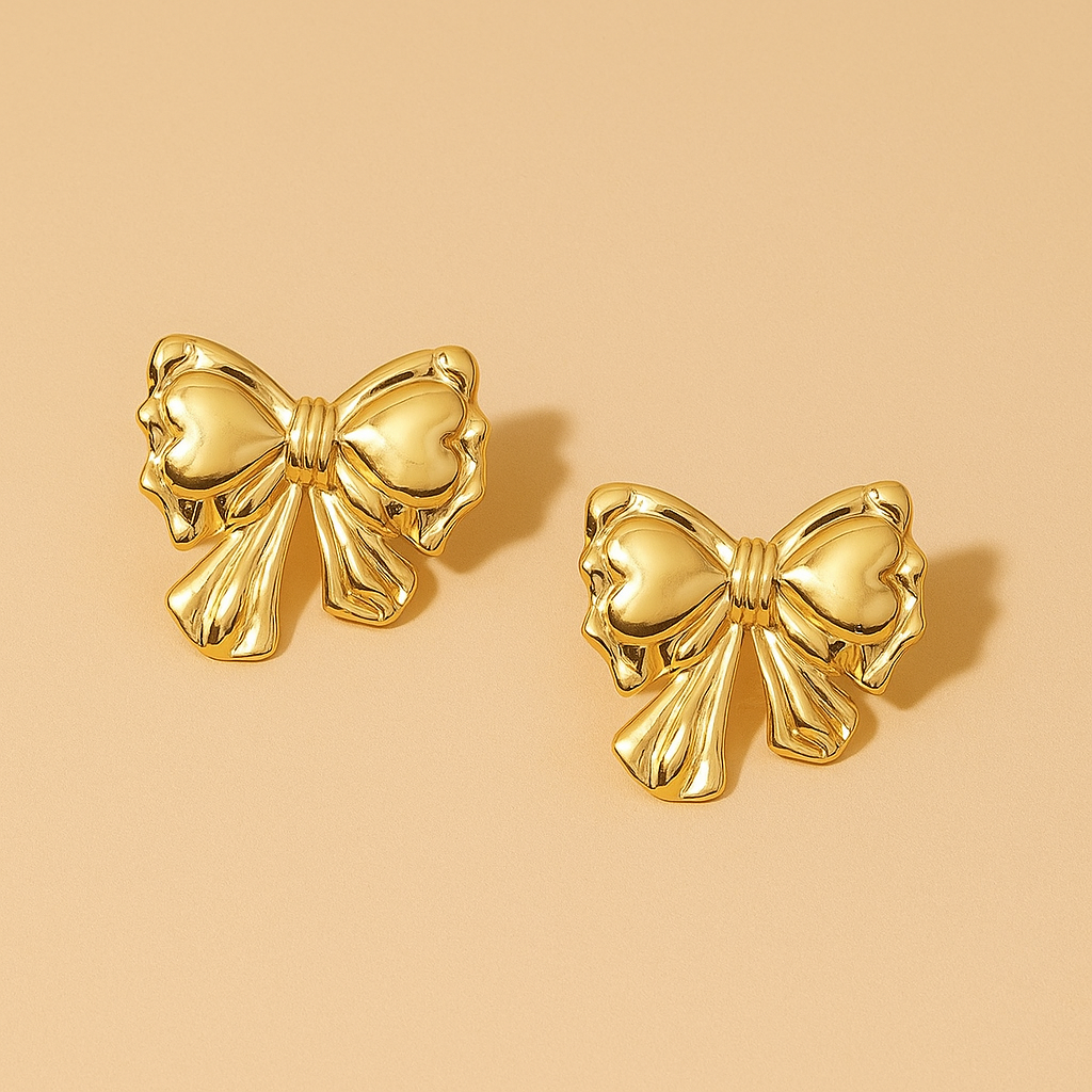 Golden bow-shaped earrings on a beige background