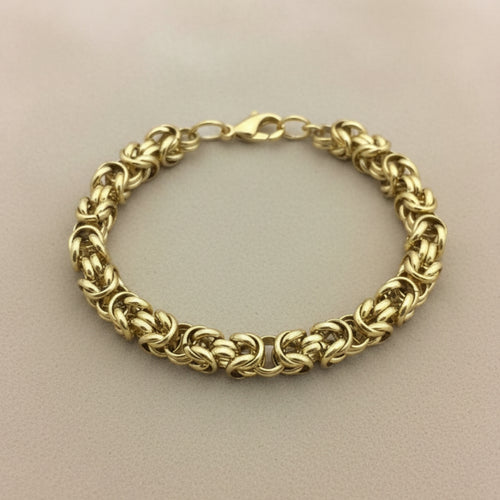 Gold chain bracelet on a beige background