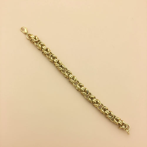 Gold chain bracelet on a beige background