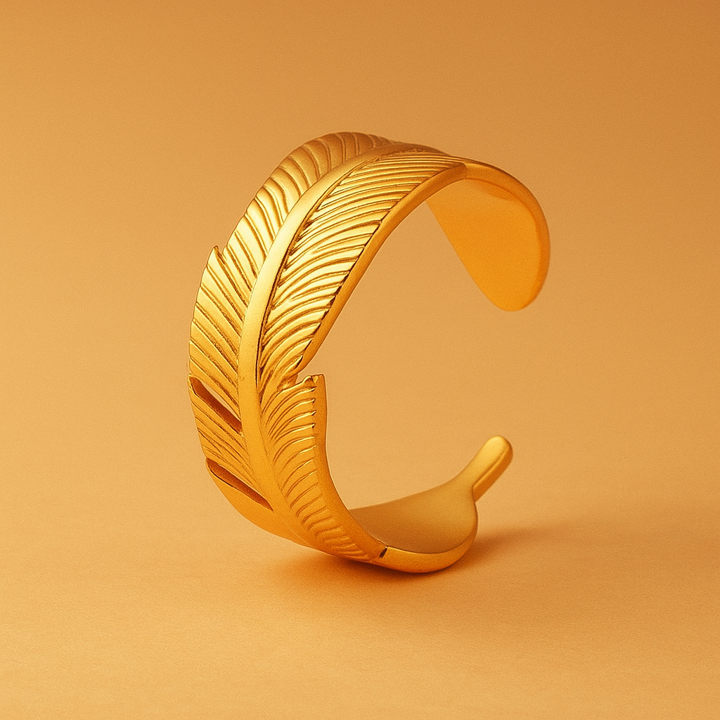 Gold feather-shaped ring on a matching gold background