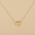 Gold necklace with a heart-shaped pendant on a beige background