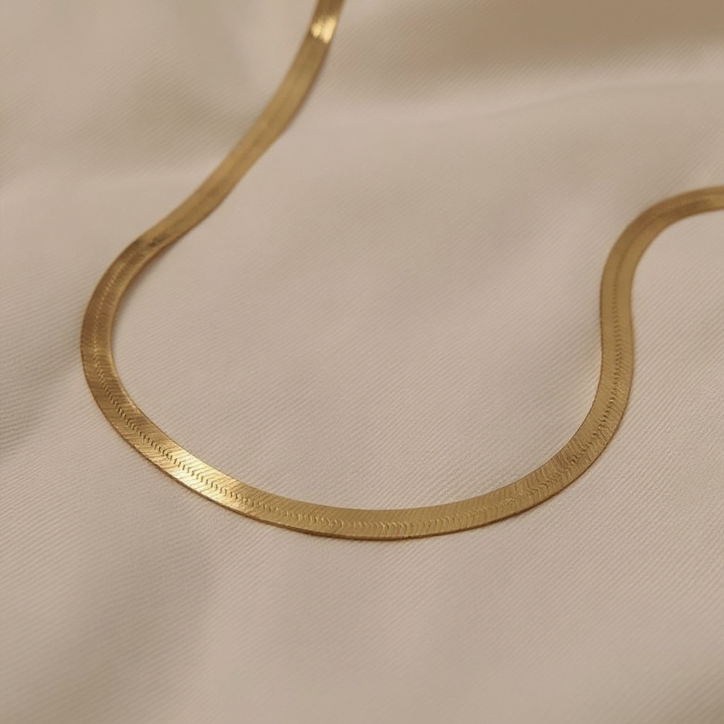Golden Herringbone Necklace on a beige fabric background