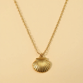 Gold necklace with a seashell pendant on a beige background