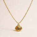 Gold shell pendant necklace on a beige background