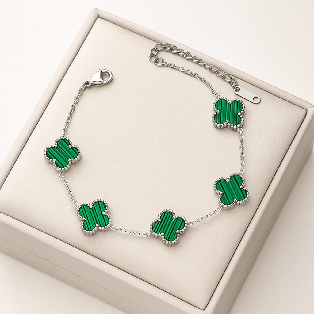 Silver bracelet with green clover-shaped charms on a beige box