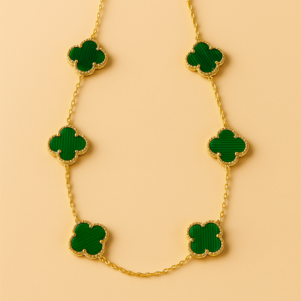Gold necklace with green clover-shaped pendants on a beige background
