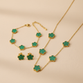 Gold necklace,bracelet and earrings with Green flower-shaped pendants on a beige background
