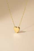 Gold heart-shaped pendant necklace on a beige background