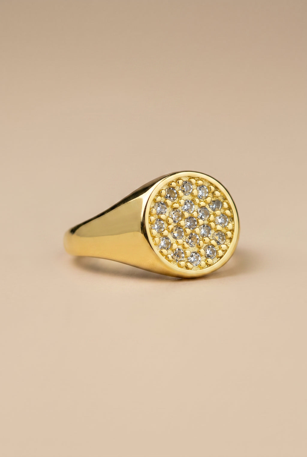 Gold ring with diamond accents on a beige background