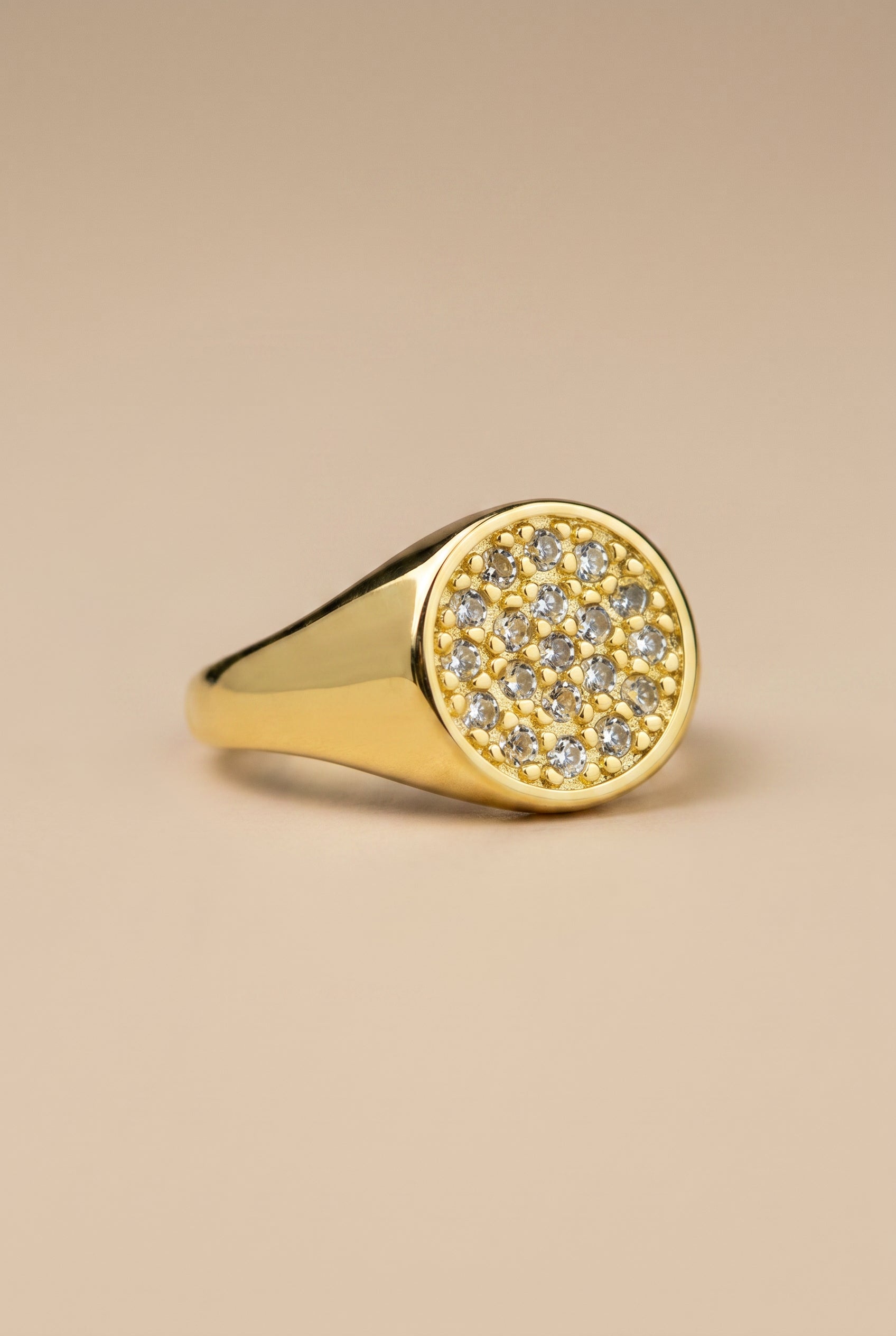 Gold ring with diamond accents on a beige background