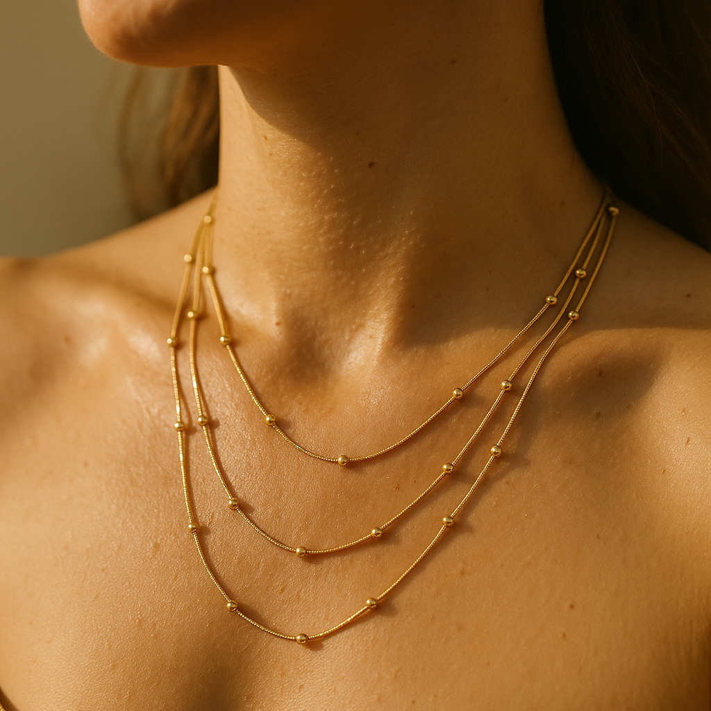 Close-up of a person wearing a gold necklace with a soft focus background