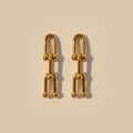 Gold chain-style earrings on a beige background