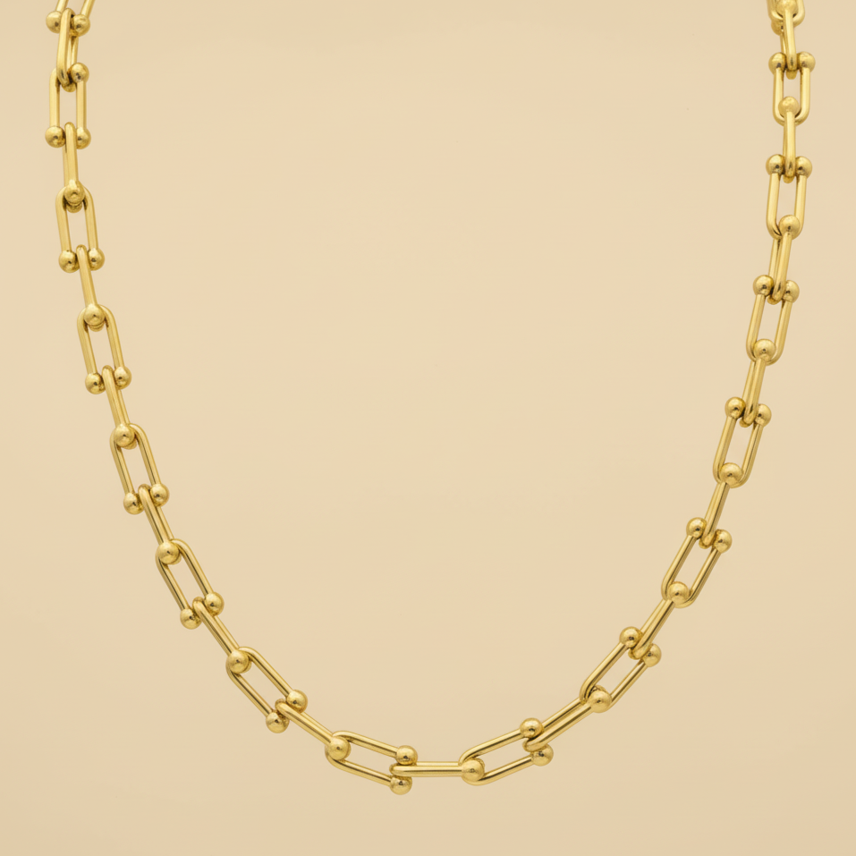 Gold chain necklace on a beige background