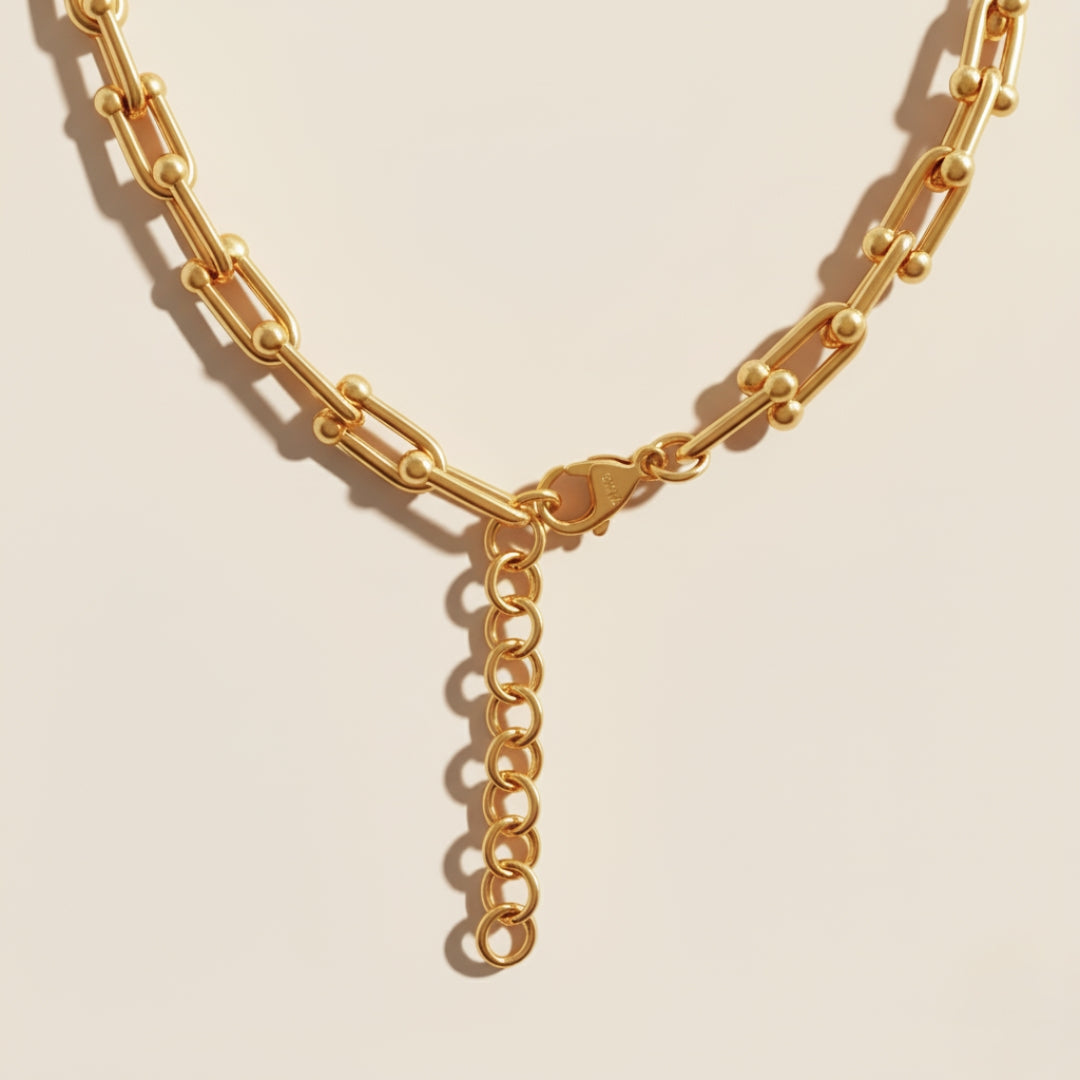 Gold chain necklace on a beige background