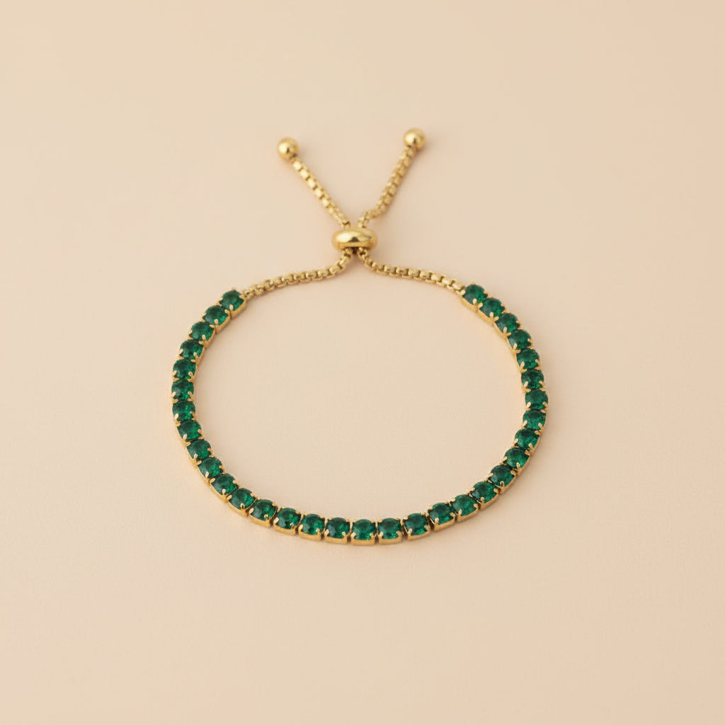 Gold bracelet with green gemstones on a beige background