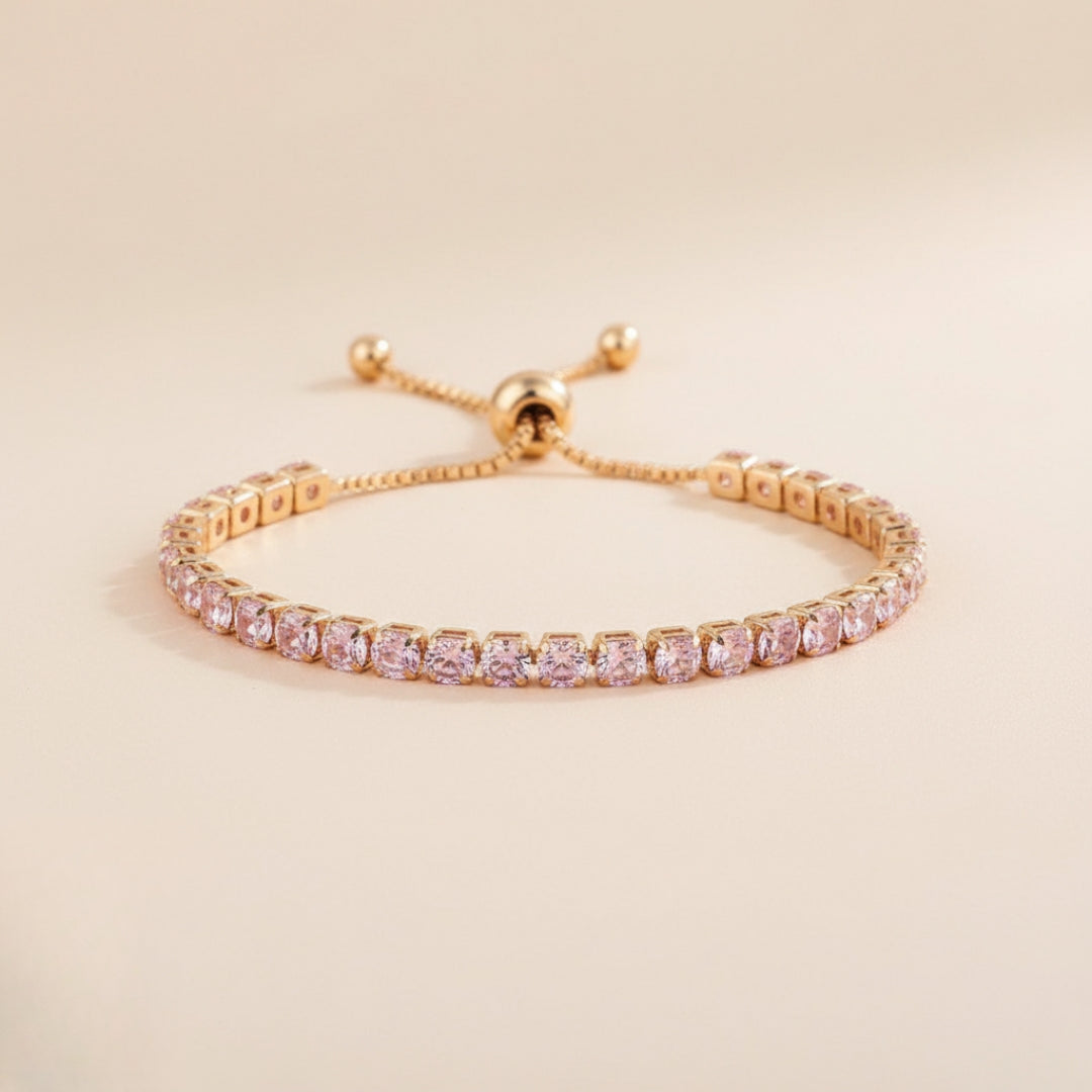 Gold bracelet with pink gemstones on a beige background